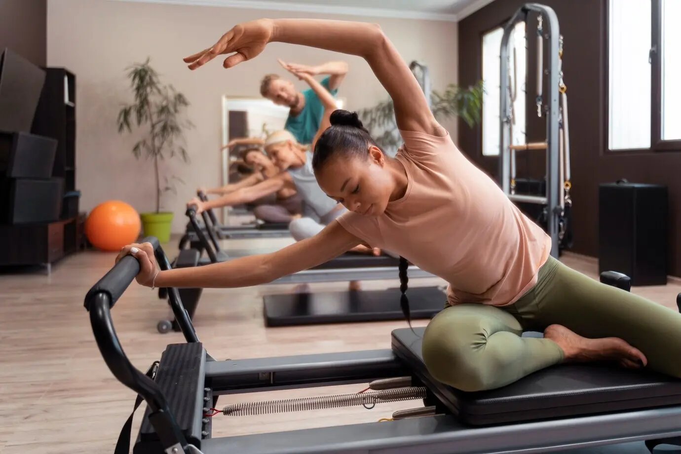 Люди на занятии по пилатесу на реформерах тренируют свои тела.