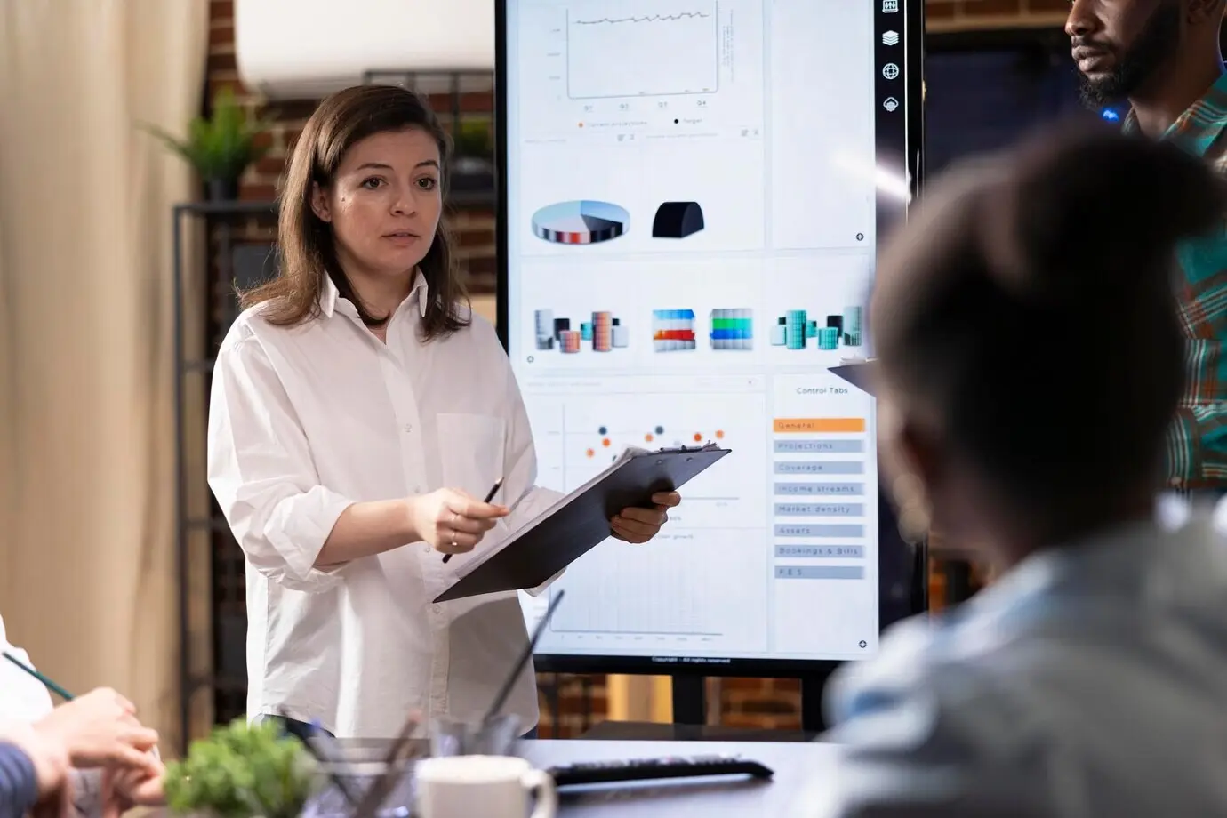 Женщина европейской внешности представляет планы проекта, держа планшет для бумаг.